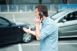 man calling the police after a car crash