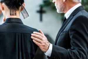 man reassuring woman at a funeral