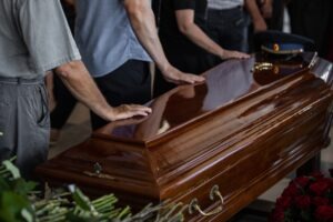 mourners with their hands on a coffin