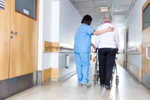 nurse walking an old woman down the hall