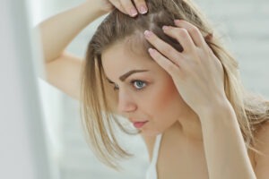 woman examining hair loss in the mirror
