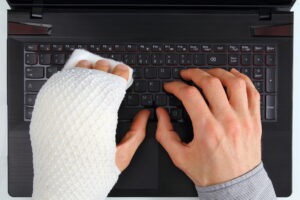 person typing with broken hand