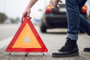 man putting cone in street at accident scene