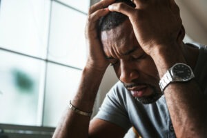 A man holding his head, wondering about the average settlement for traumatic brain injury.