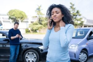 A woman on the phone after a car accident, wondering if her insurance will go up after a claim that is not her fault.